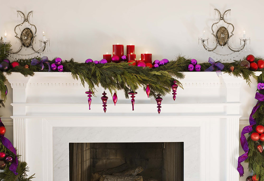 Cedar bough with candles and ornaments on a fireplace mantle